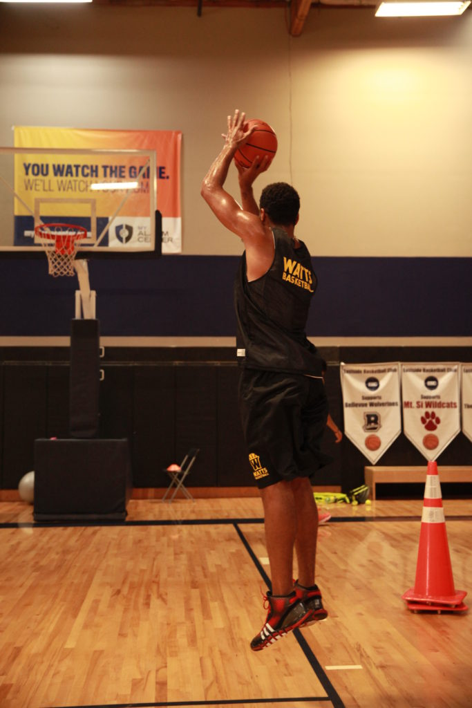 Basketball player jumping to shoot in gym