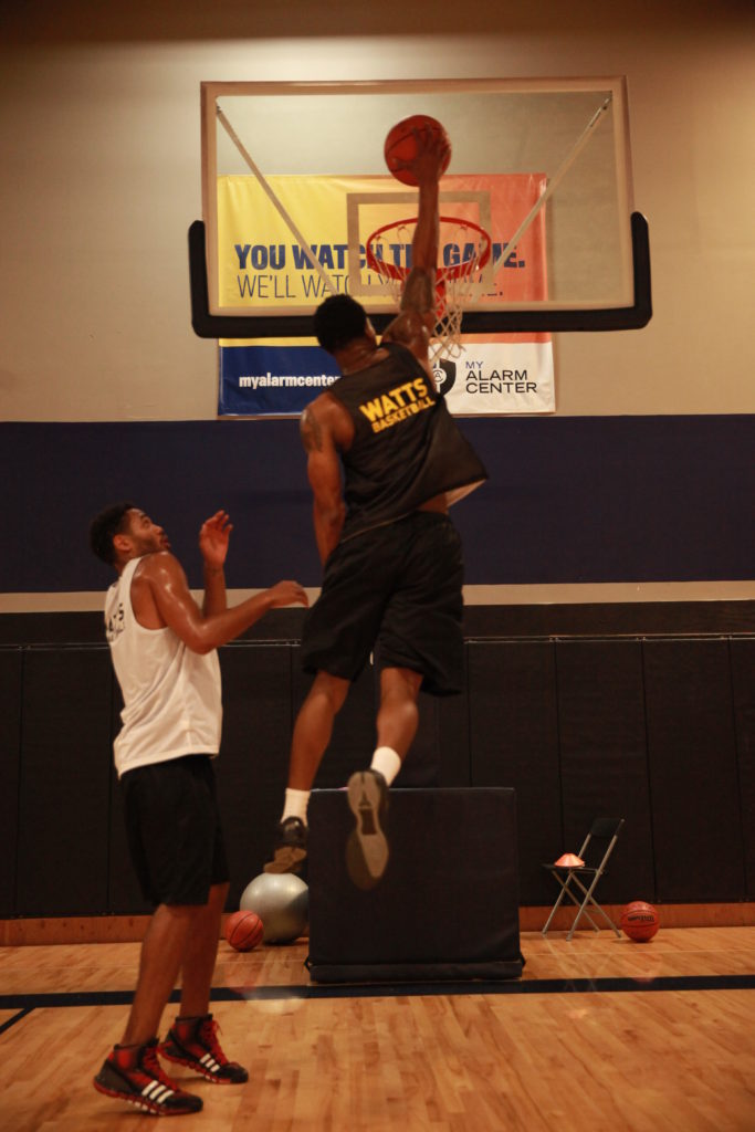 Basketball player dunking while teammate watches