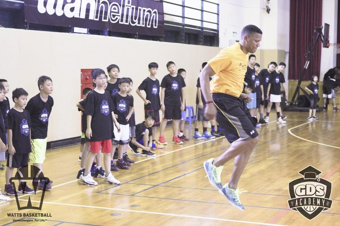 Basketball coach jumps while children watch