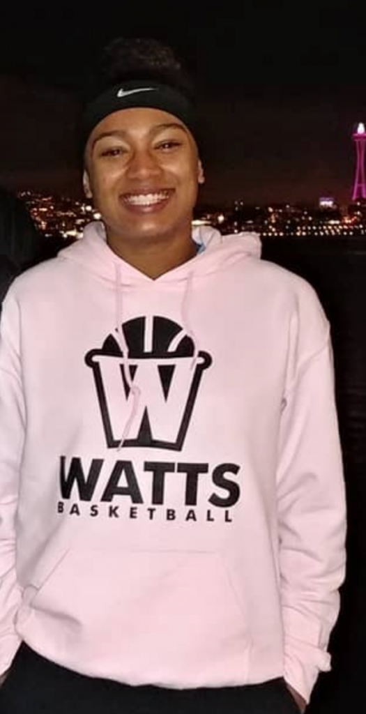Smiling person in pink Watts basketball hoodie