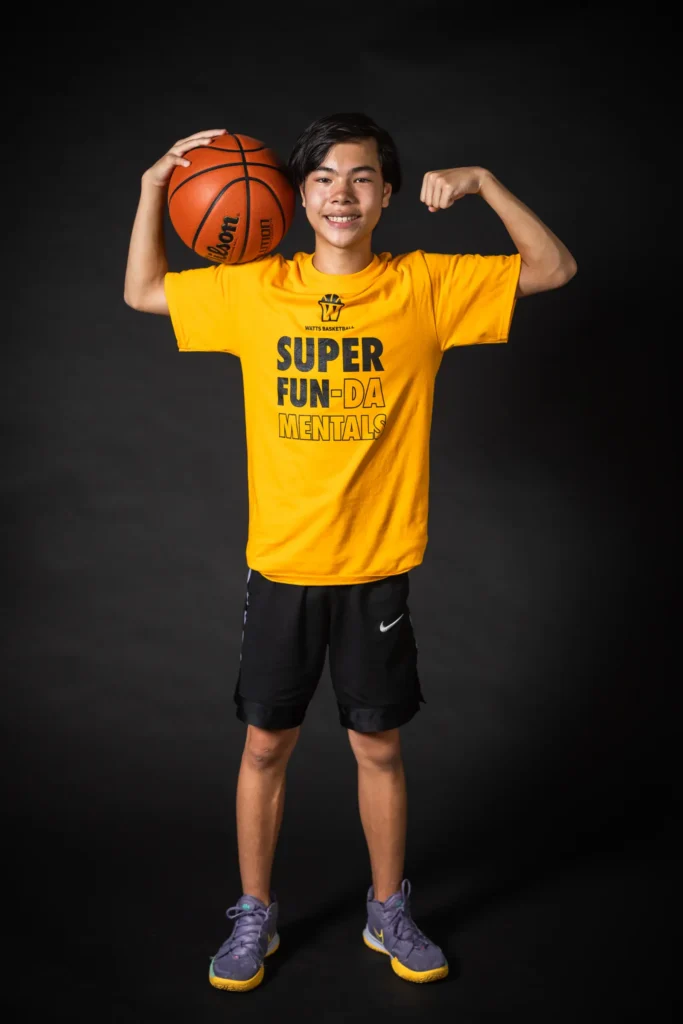 Smiling teen in yellow shirt, flexing with basketball