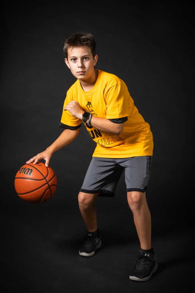 Boy dribbling basketball wearing yellow shirt