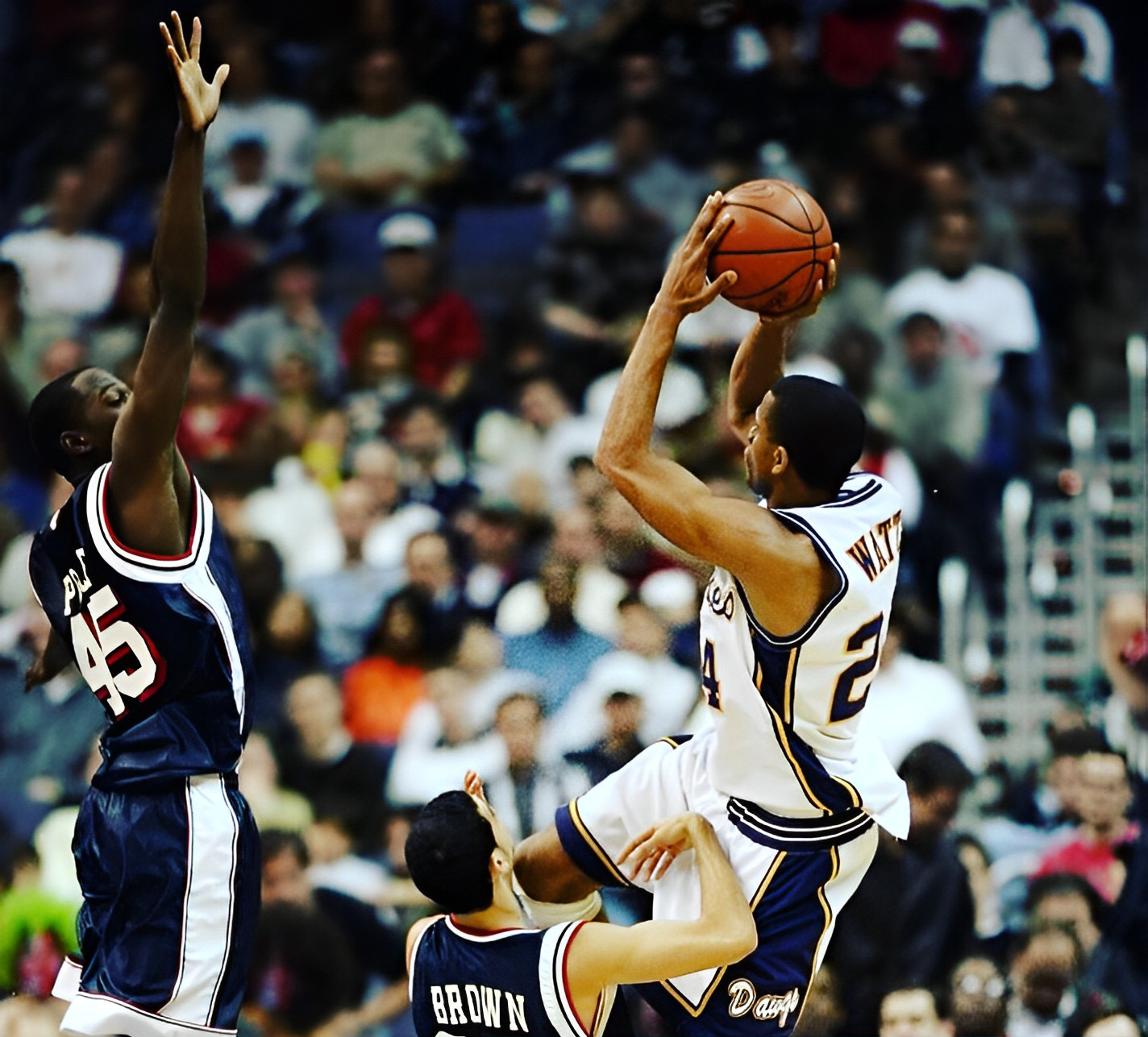 Basketball player shooting over two defenders